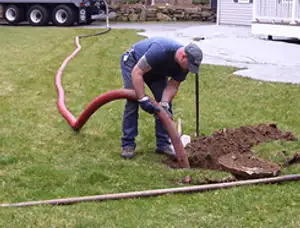 Septic pumping technician servicing a residential septic tank with a vacuum hose in Cleveland, OH