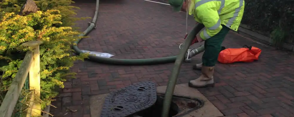Septic tank cleaning technician servicing a septic tank with a vacuum hose in Cleveland, OH