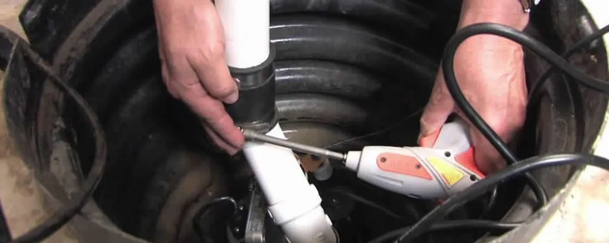 Sump pump installation technician connecting PVC discharge piping in Cleveland, OH