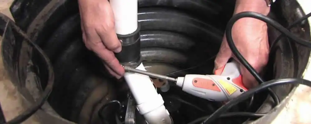 Sump pump installation technician connecting PVC discharge piping in Cleveland, OH