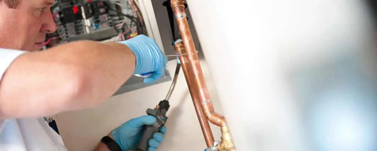 Water heater repair technician testing copper pipe connections and controls in Cleveland, OH