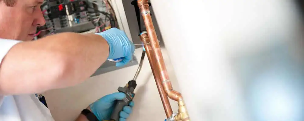 Water heater repair technician testing copper pipe connections and controls in Cleveland, OH